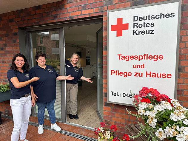 Drei Frauen vor einer Tagespflegeeinrichtung des Deutschen Roten Kreuzes.