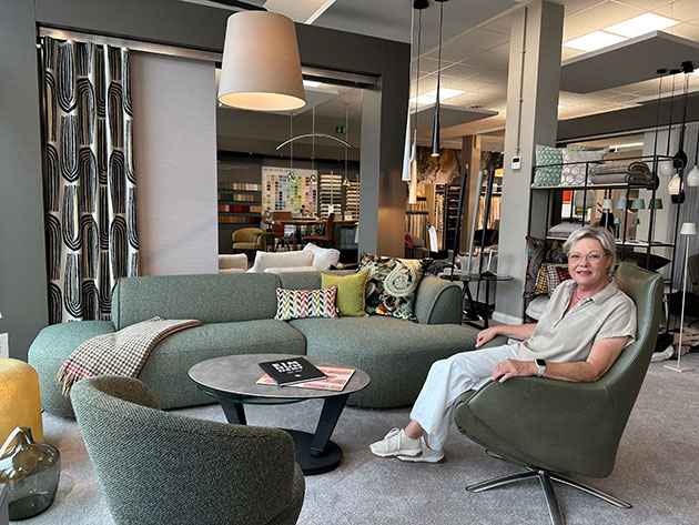 Frau sitzt auf einem grünen Stuhl in einem modernen Wohnzimmer.