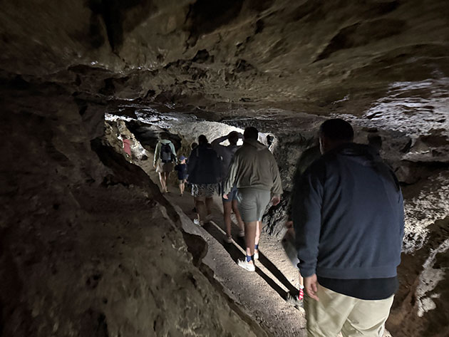 Gruppe von Menschen erkundet eine enge, natürliche Höhle.
