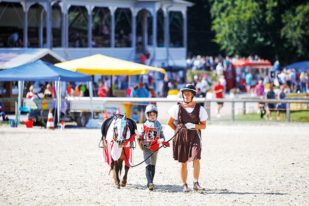 Zwei Personen führen ein Pony auf einer Veranstaltung.
