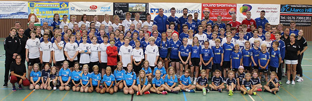 Große Gruppenfoto in einer Sporthalle mit Personen in Sportkleidung.