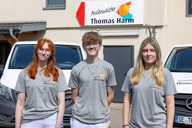 Drei Personen vor dem Malereibetrieb Thomas Harm.