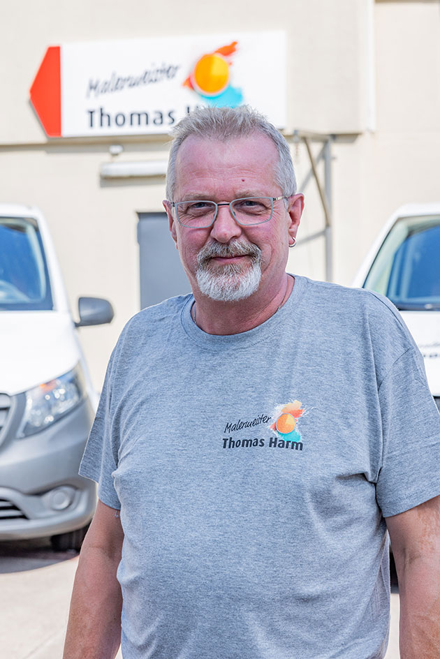 Mann in grauem Shirt vor weißen Lieferwagen