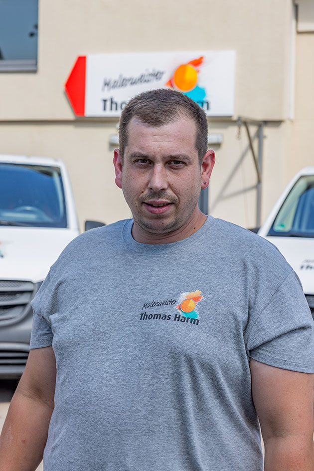 Mann im grauen Shirt vor weißen Lieferwagen.