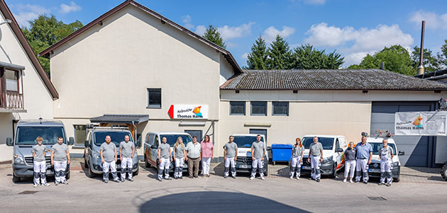 Malerteam steht vor Firmenfahrzeugen in Hof.