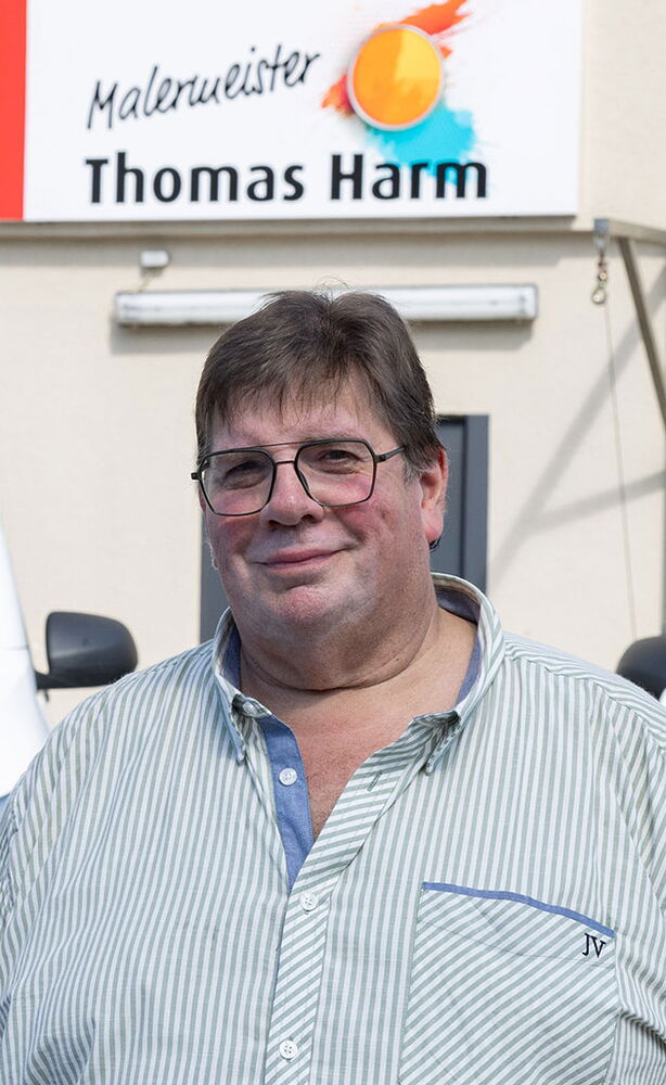 Mann mit Brille vor Schild Malermeister Thomas Harm