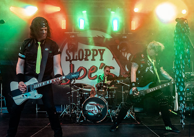 Band spielt Rockmusik auf einer beleuchteten Bühne.