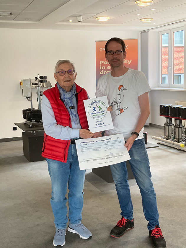 Zwei Personen halten eine Spendenurkunde und einen großen Scheck.