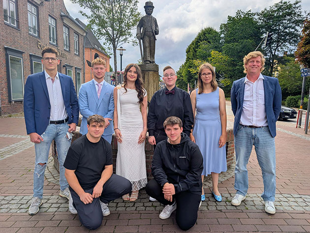 Gruppe von acht Personen vor einer Statue in der Stadt.