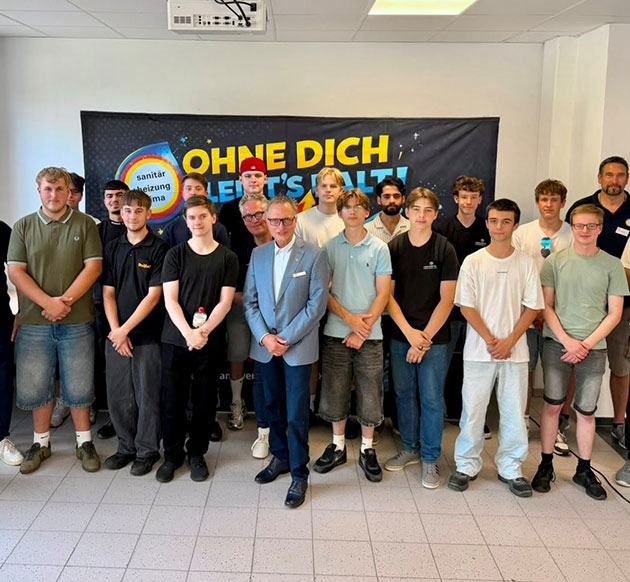 Gruppe von Männern vor einem Banner bei einem Event.