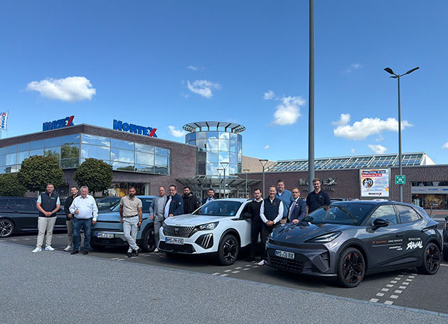 Gruppe vor Autos und Gebäude mit Nortex-Logo.