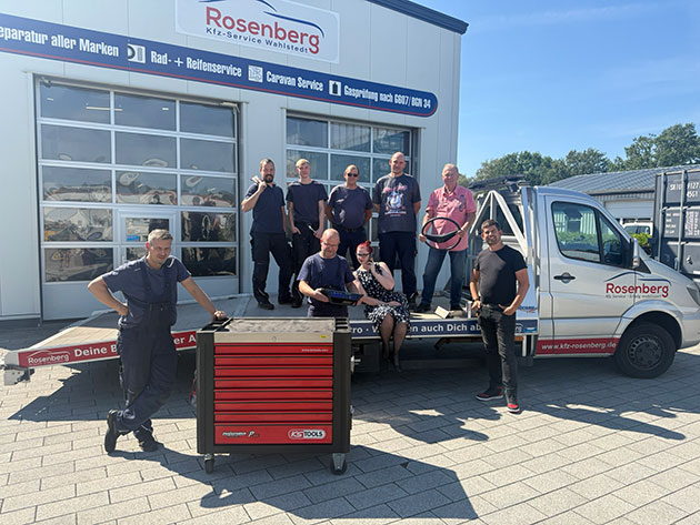 Gruppe von Menschen vor einem Werkstatt-Lkw mit Werkzeugkasten.