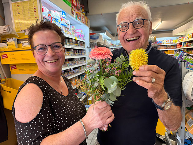 Mann und Frau lächeln mit Blumenstrauß im Laden.