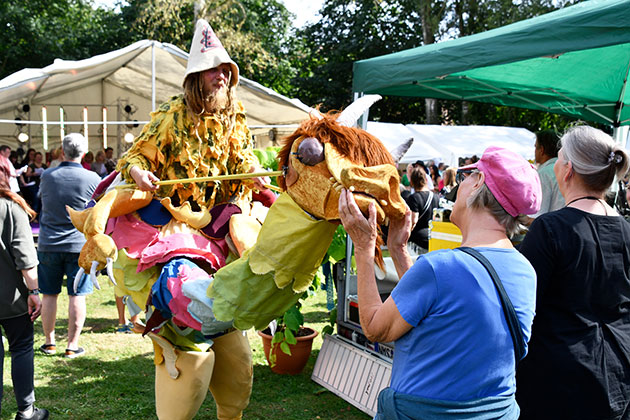 Person in Kostüm auf Stelzen auf einem Festival.