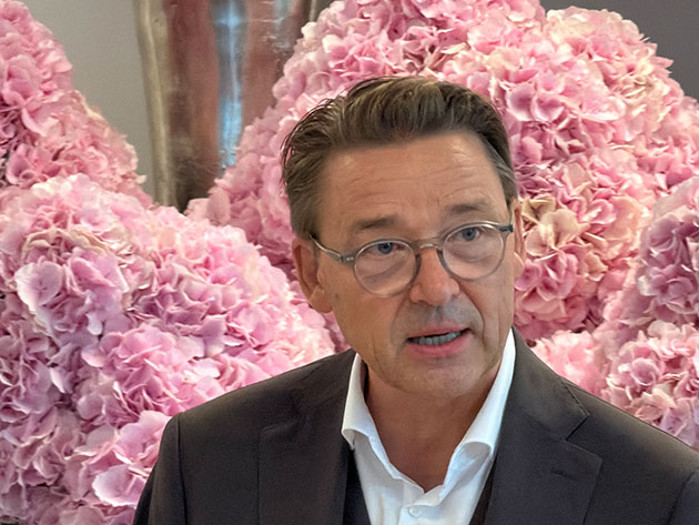 Mann mit Brille vor rosa Hortensienblüten