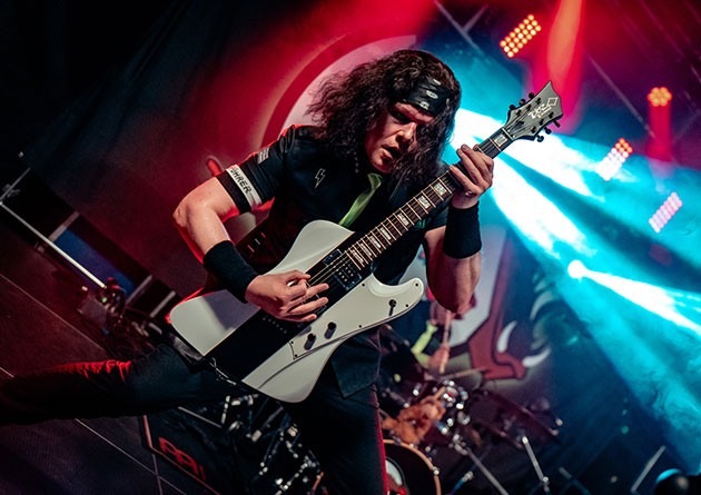 Gitarrist spielt auf der Bühne mit weißer Gitarre.