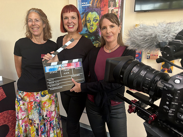 Drei Frauen posieren mit Filmausrüstung in einem Raum.