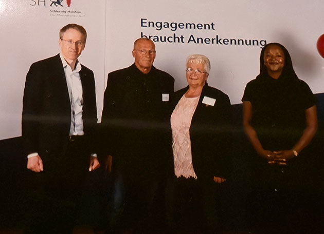Vier Personen vor einem Plakat bei einem Event.