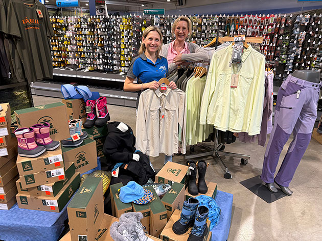 Zwei Frauen präsentieren Outdoor-Kleidung und Schuhe im Geschäft.