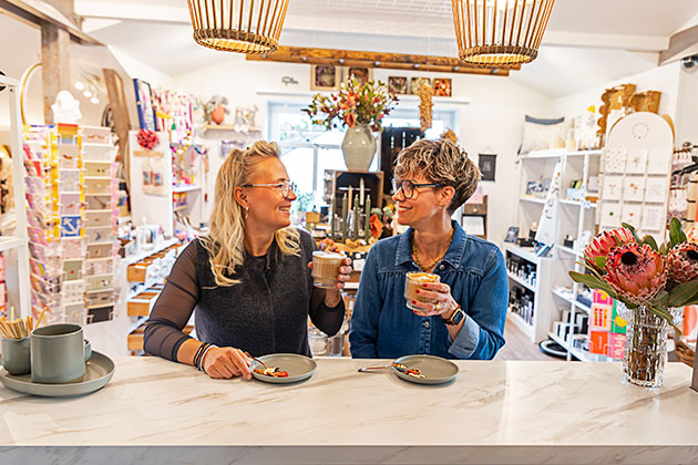 Zwei Frauen trinken Kaffee in einem gemütlichen Laden.
