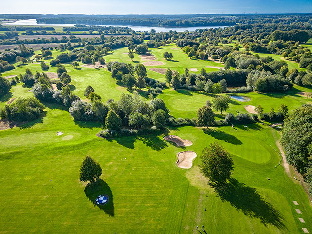 Luftaufnahme eines grünen Golfplatzes am See.