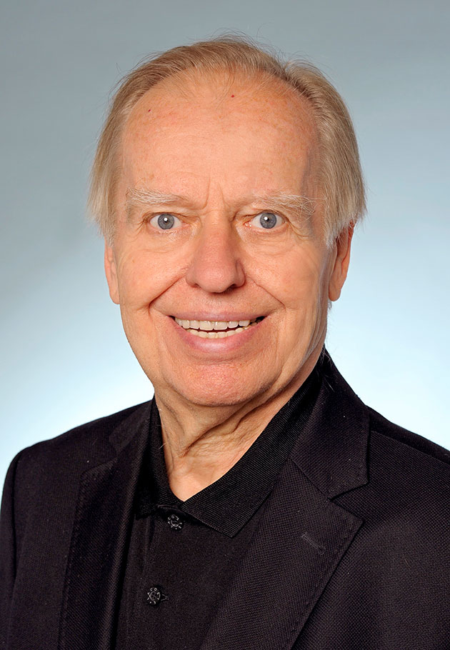 Ein lächelnder älterer Mann in schwarzem Anzug
