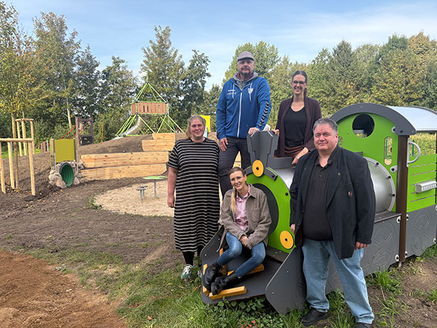 Gruppe von Menschen auf einem Spielplatz mit Holzzug.