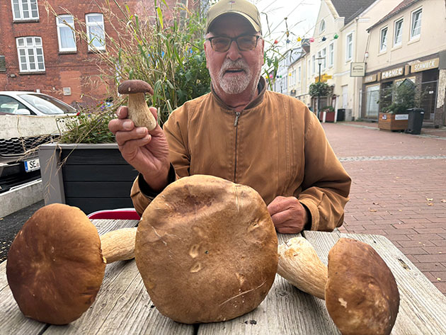 Mann präsentiert große Pilze auf einem Tisch.