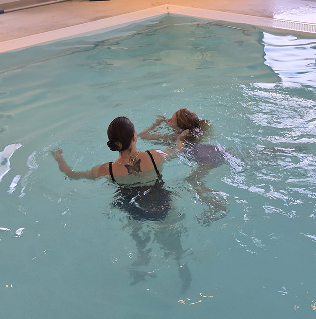 Frau lehrt Kind das Schwimmen in einem Hallenbad.