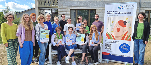 Gruppe von 16 Personen vor Plakat der seelischen Gesundheit.