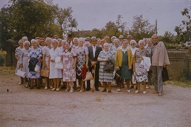 Gruppe älterer Menschen posiert draußen für ein Foto.