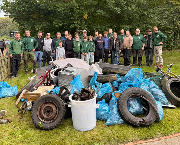 Gruppe steht hinter gesammeltem Müll im Park.