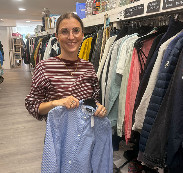 Frau hält Hemd in Secondhand-Laden.