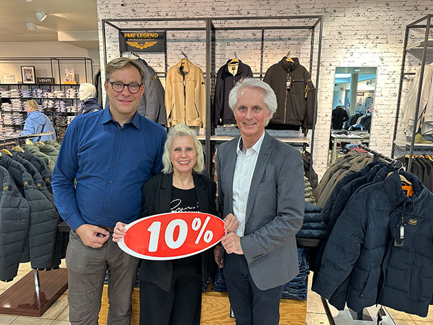 Drei Personen halten ein Schild mit 10% in einem Bekleidungsgeschäft.