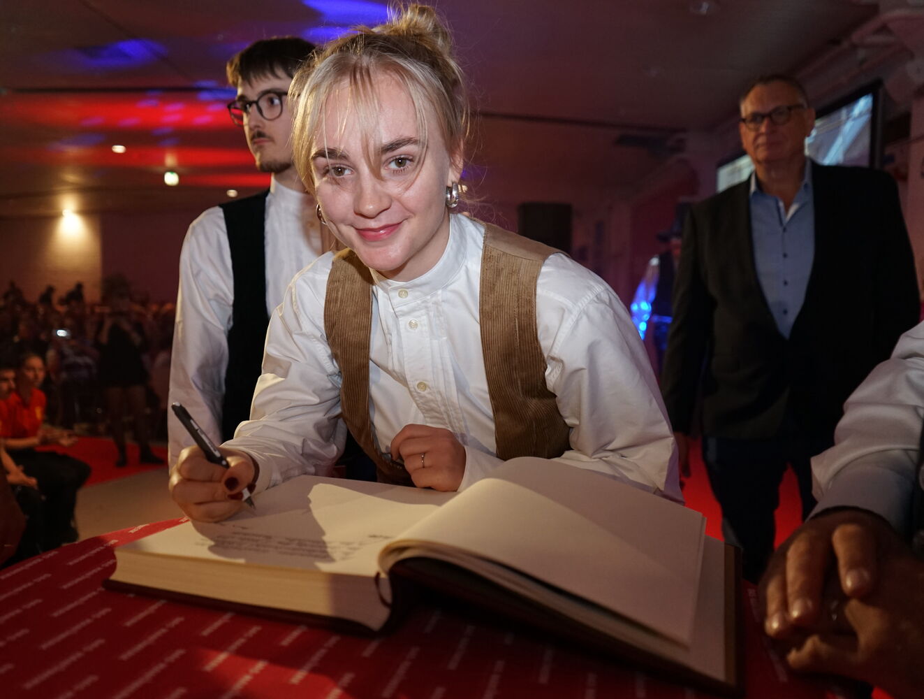 Frau unterschreibt in einer Festhalle ein Buch.