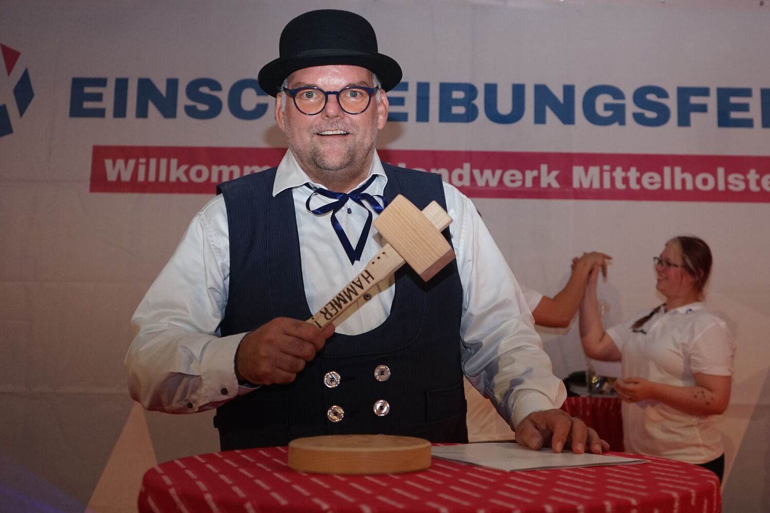 Mann mit Hammer bei Einschreibungsfeier im Handwerk