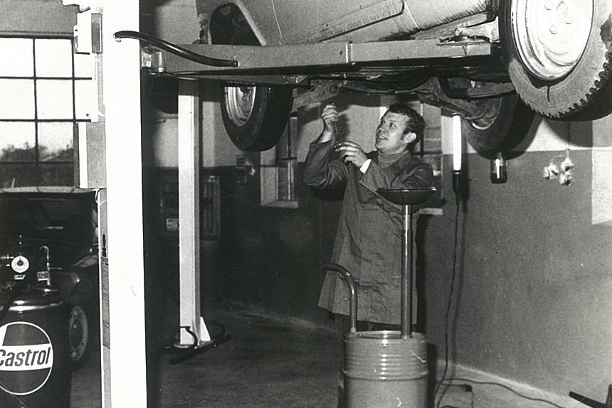 Mechaniker arbeitet an einem Auto auf einer Hebebühne.