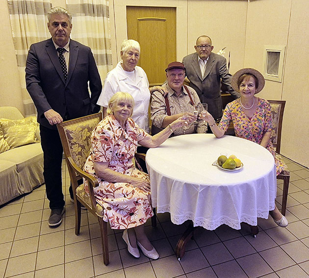 Gruppe von sechs Menschen an einem Tisch mit Obst.
