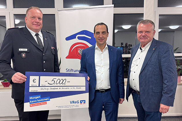Drei Männer halten einen Scheck über 5000 Euro.
