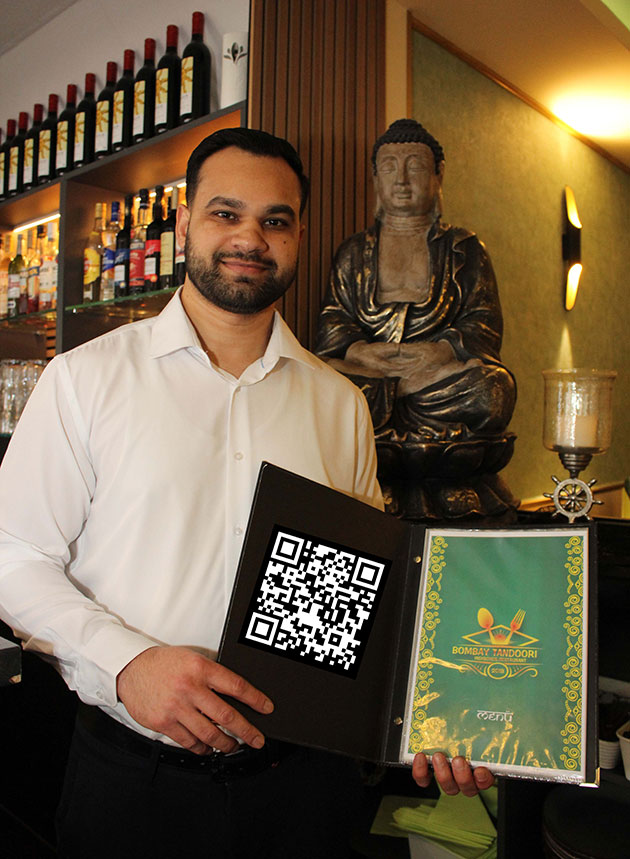 Mann hält Speisekarte mit QR-Code im Restaurant.