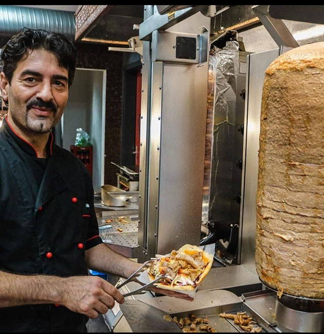 Mann bereitet Döner Kebab an der Theke zu.