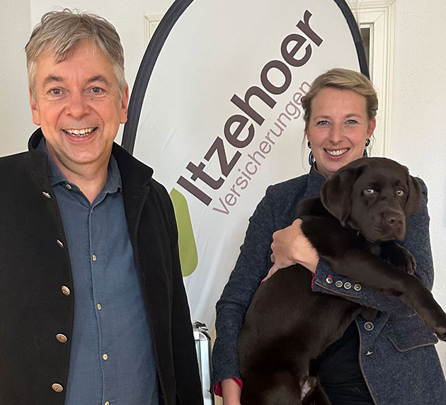 Zwei Personen mit Hund vor Itzehoer Banner.