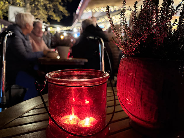 Kerze und Pflanze auf Tisch im Freien bei Nacht.