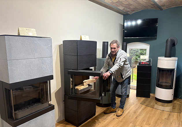 Mann legt Brennholz in modernen Kamin in einem Ausstellungsraum.