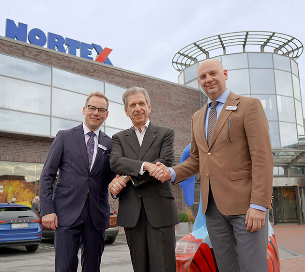 Drei Männer vor einem Gebäude mit Nortex-Logo