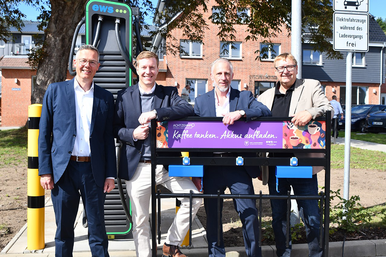 Vier Männer stehen vor einer Ladestation im Freien.
