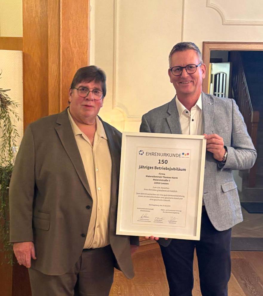 Zwei Männer halten eine Ehrenurkunde für 150 Jahre Jubiläum.
