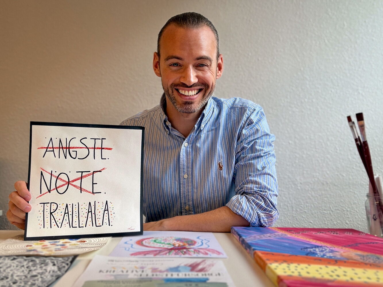 Mann am Tisch mit Schild: Ängste, Nöte, Trallala.