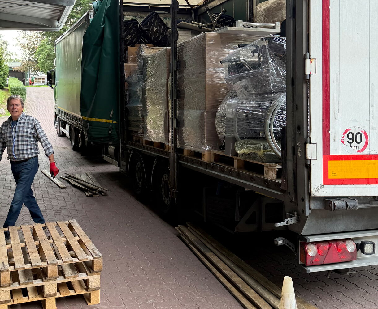 Lkw mit geöffnetem Anhänger und Paletten beladen.